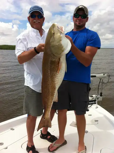 Two anglers on the bow holding up a bull redfish near Venice, Louisiana