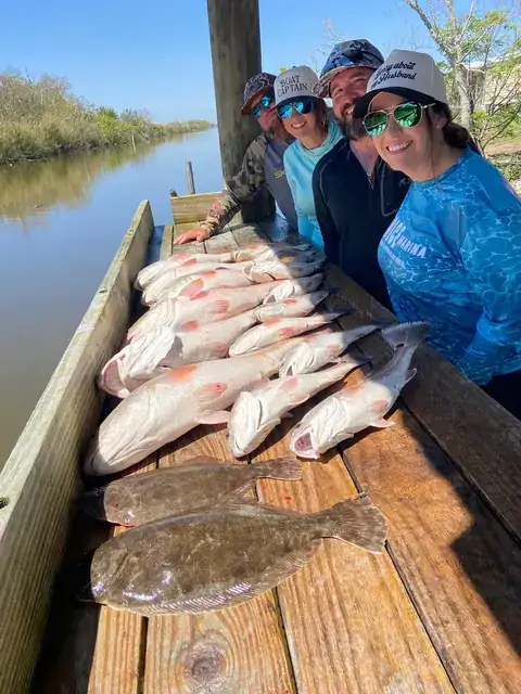 Anglers beside a catch of redfish and flounder on the cleaning dock in Venice, Louisiana