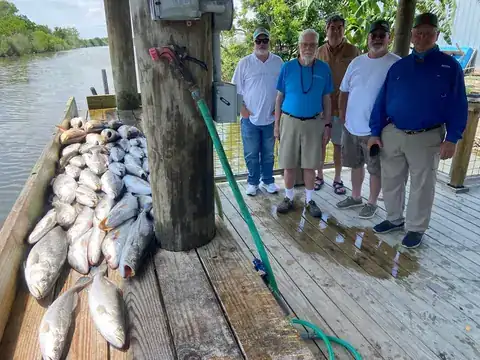 Five anglers standing beside their catch on the cleaning dock in Venice, Louisiana