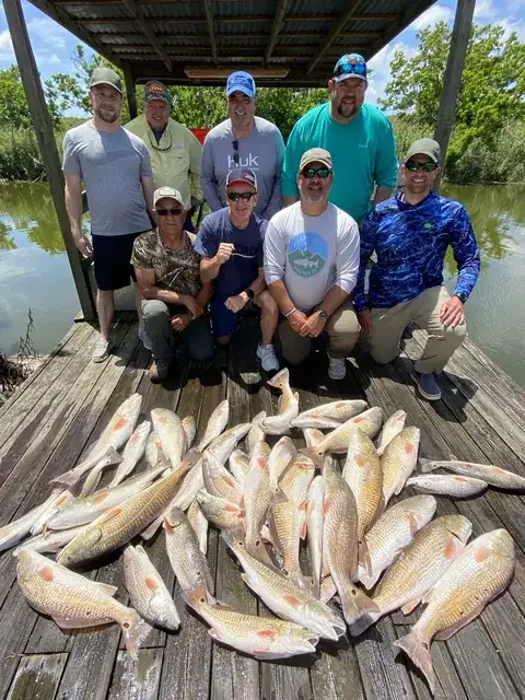 A group of anglers behind a large catch of redfish on the dock in Venice, Louisiana