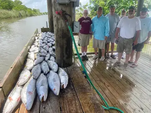 A group of anglers standing beside their catch on the cleaning dock in Venice, Louisiana