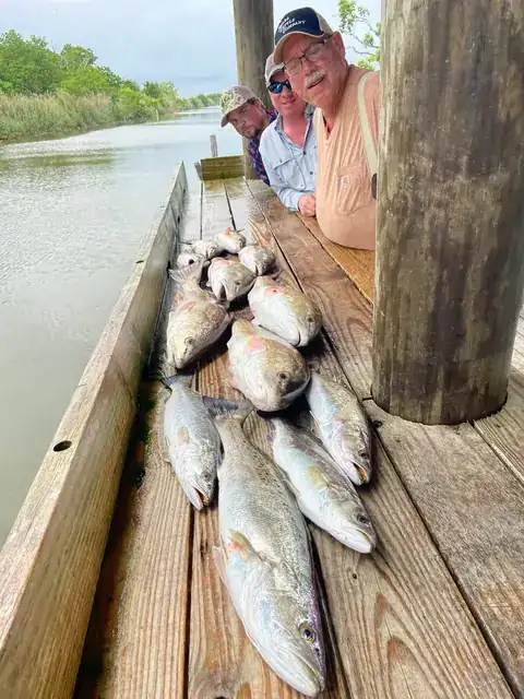 Three anglers beside their catch on the cleaning dock in Venice, Louisiana