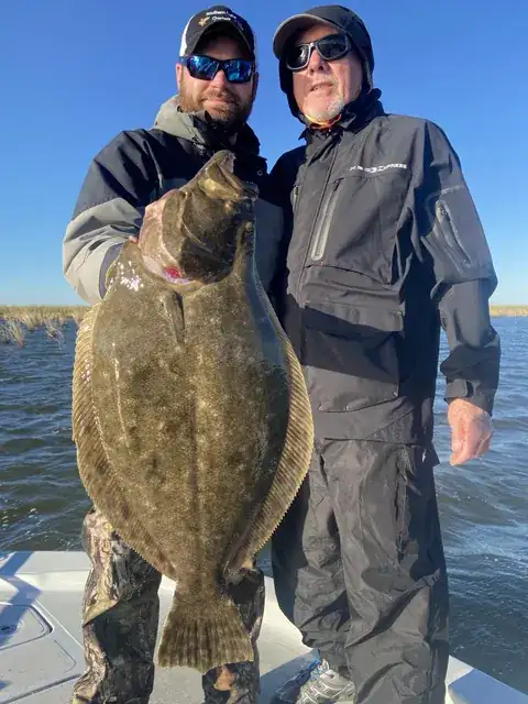 Two anglers on the boat holding up a large flounder near Venice, Louisiana