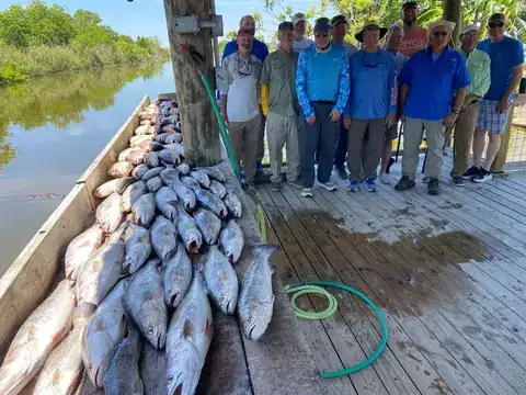 A group of anglers on the dock beside a day's catch