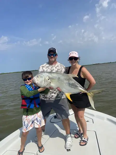 A young angler and two adults holding a jack crevalle on the bow near Venice, Louisiana