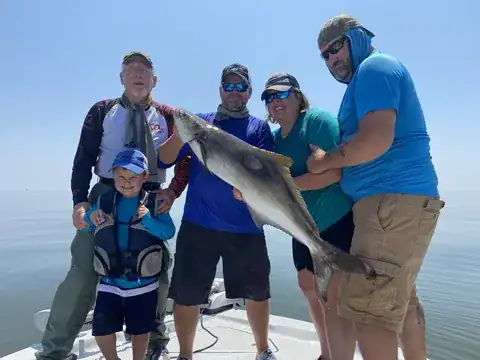 A group on the boat, with a young angler in front, holding up a large fish near Venice, Louisiana