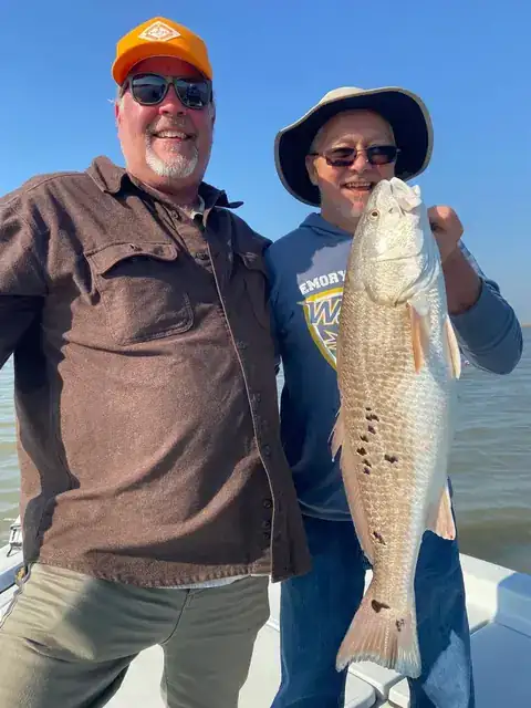 Two anglers on the bow holding a redfish upright near Venice, Louisiana
