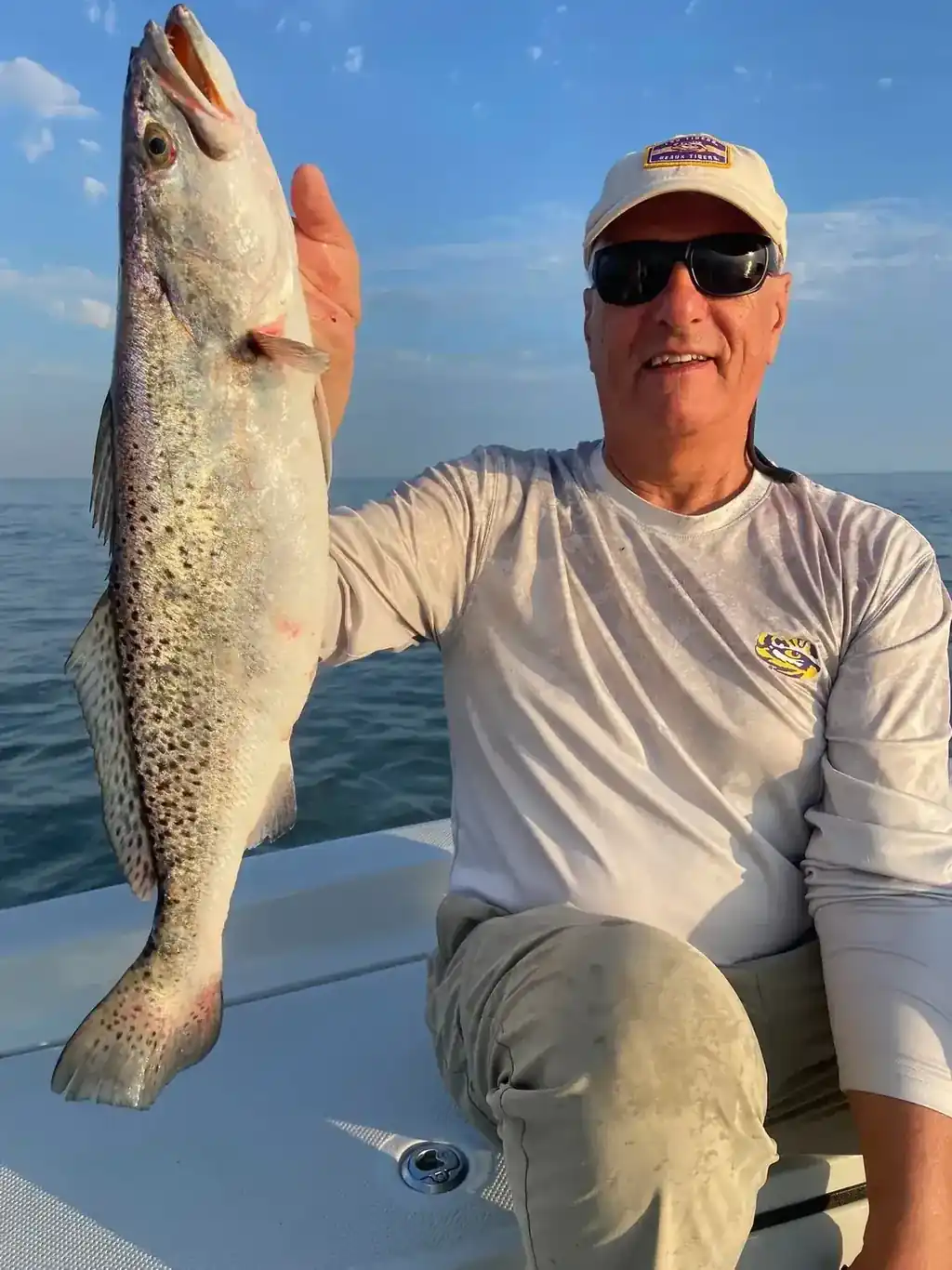 Angler holding up a large speckled trout on the bow