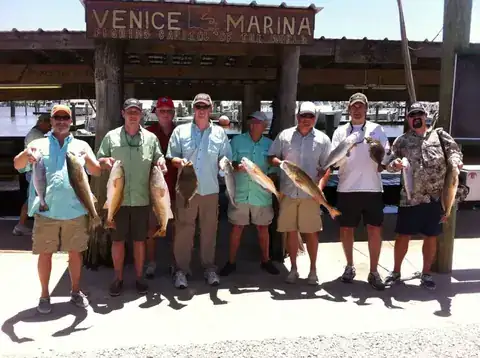 Group of anglers holding redfish under the Venice Marina sign